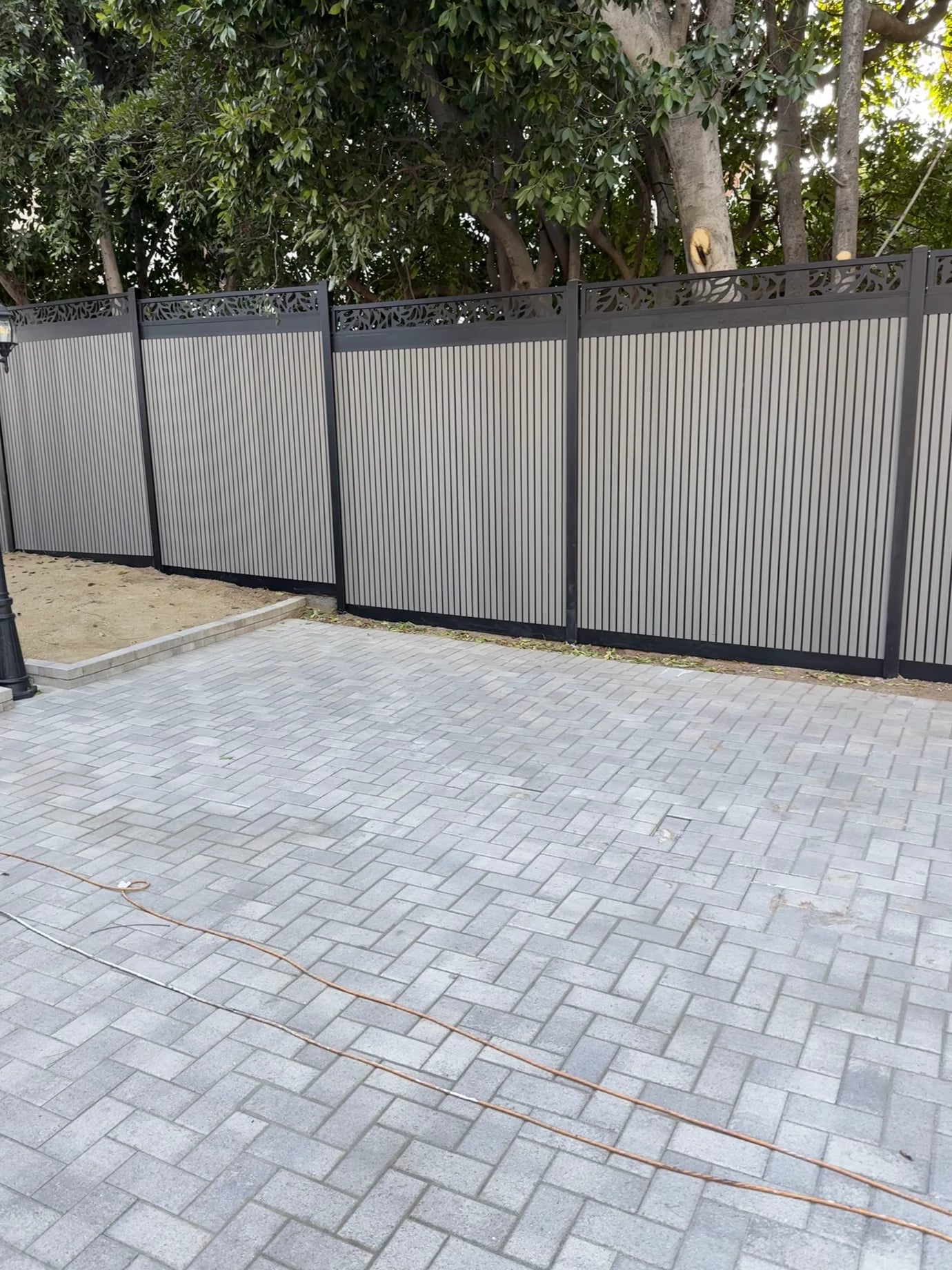 Same patio in Costa Mesa after: new gray metal privacy fence with a decorative top