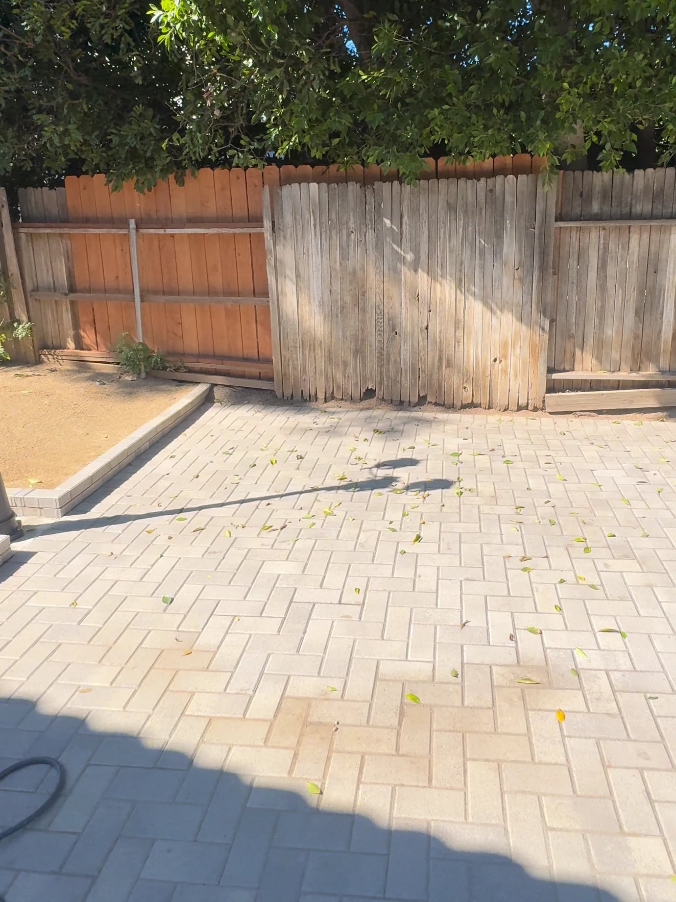 Fence in Costa Mesa before: weathered wood fence behind a paver patio
