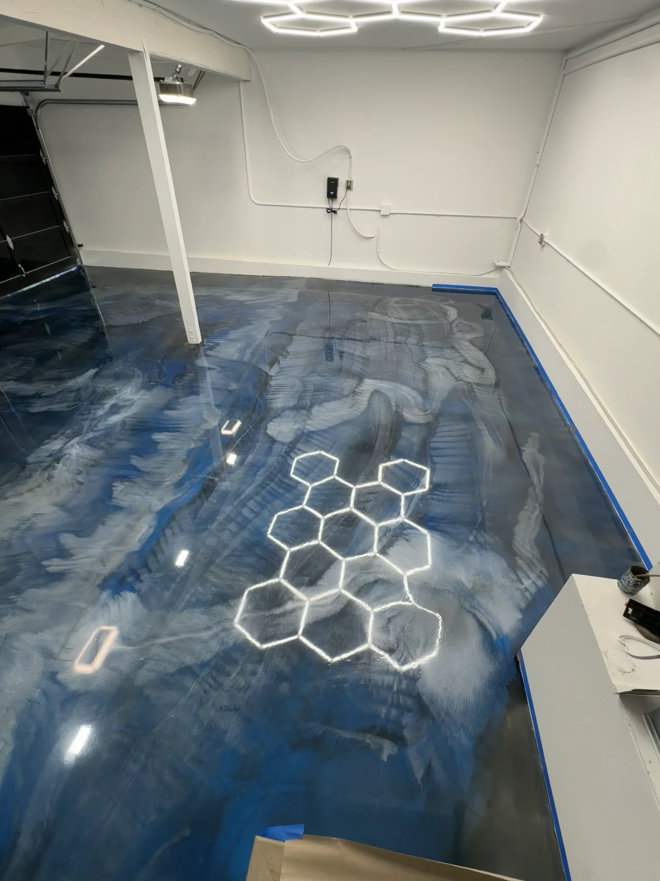 Same garage in Orange after: blue metallic epoxy floor reflecting the hexagon lights