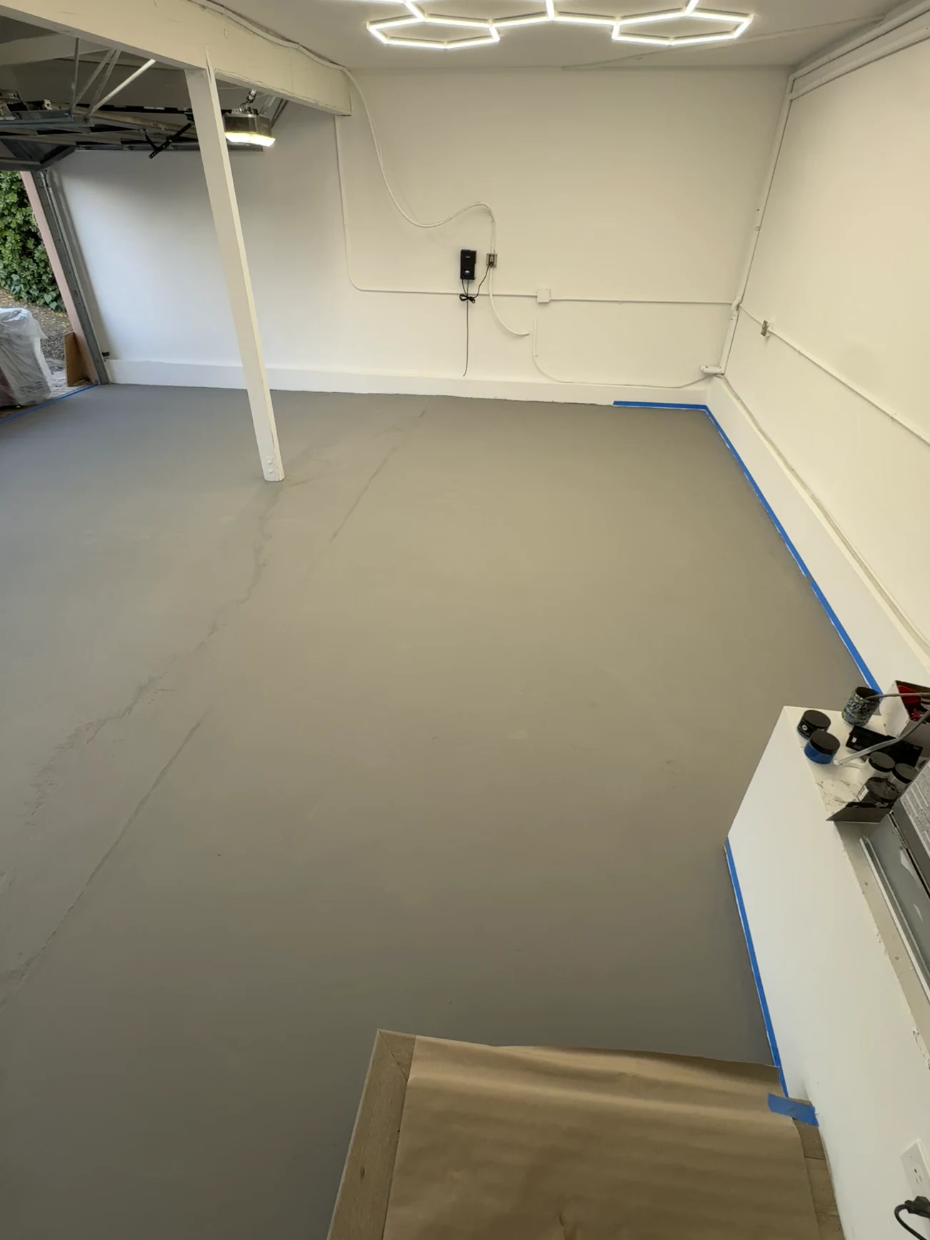 Garage in Orange before: floor in a flat gray base coat under hexagon ceiling lights