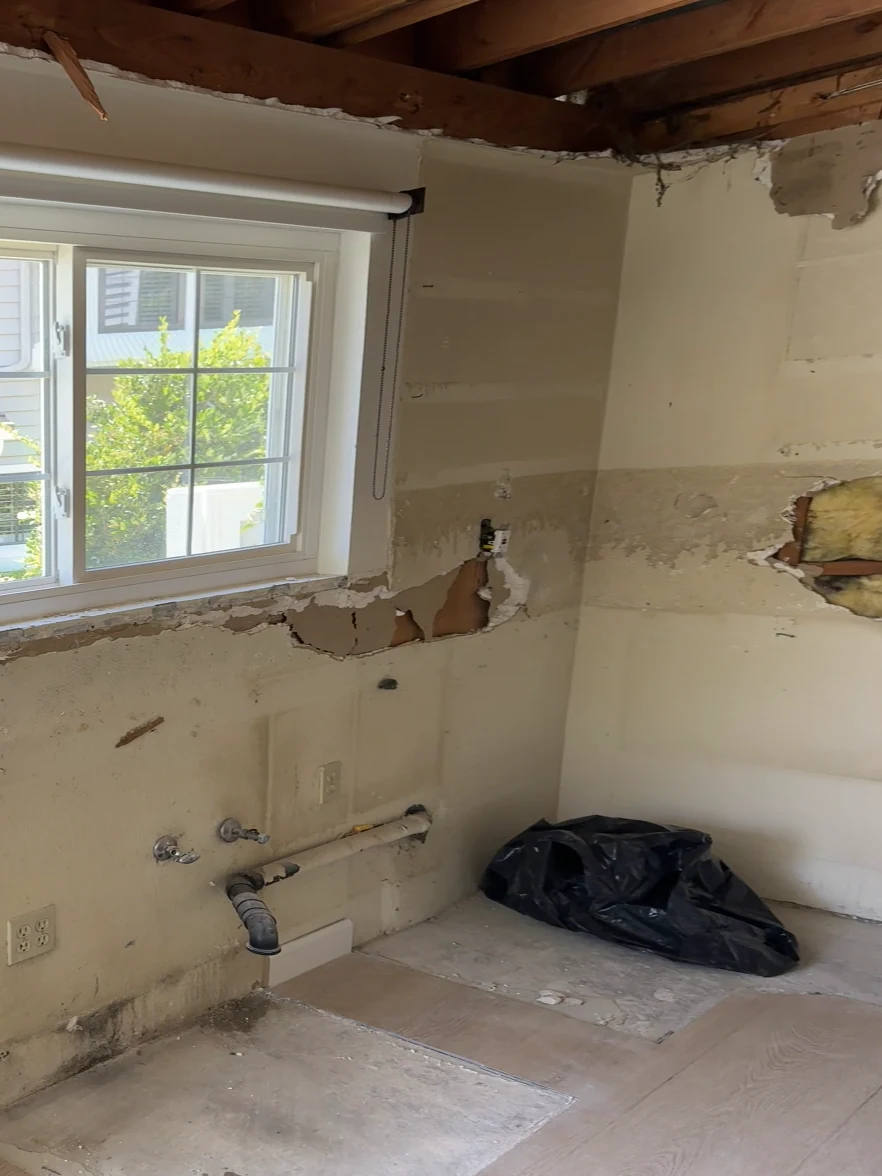Kitchen in Tustin before: ceiling opened to the joists, walls stripped around the window, plumbing stubbed out