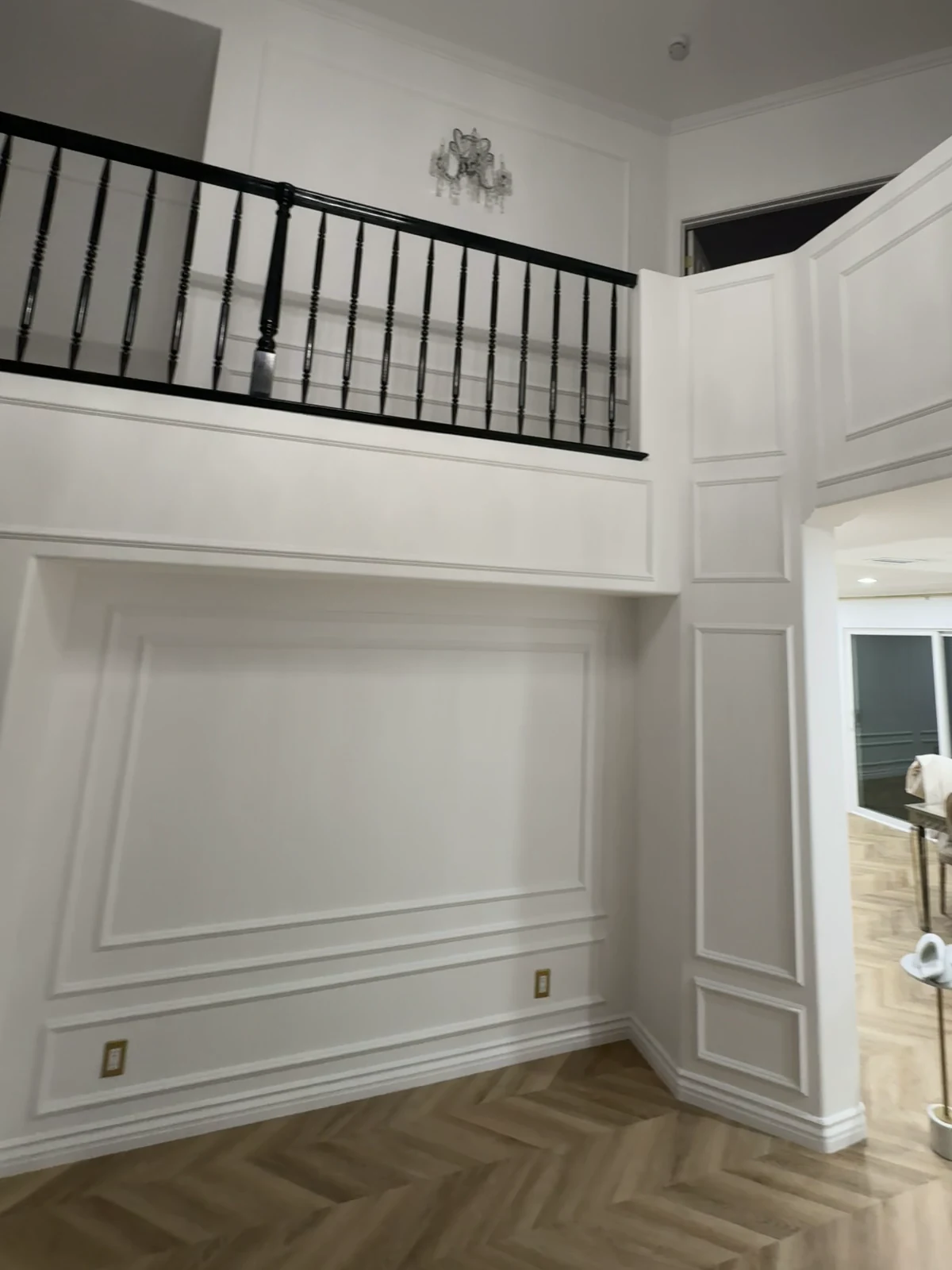 Same wall in La Cañada Flintridge after: panel molding, painted trim and a herringbone floor under the balcony