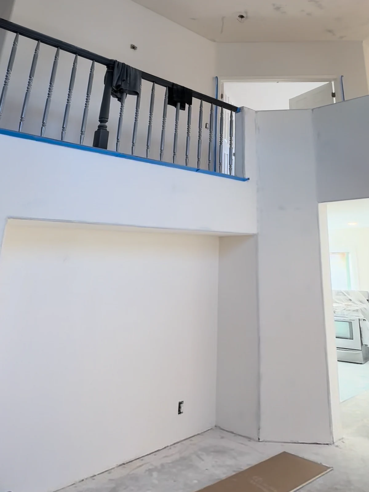 Great room in La Cañada Flintridge before: bare drywall under the balcony railing, concrete floor
