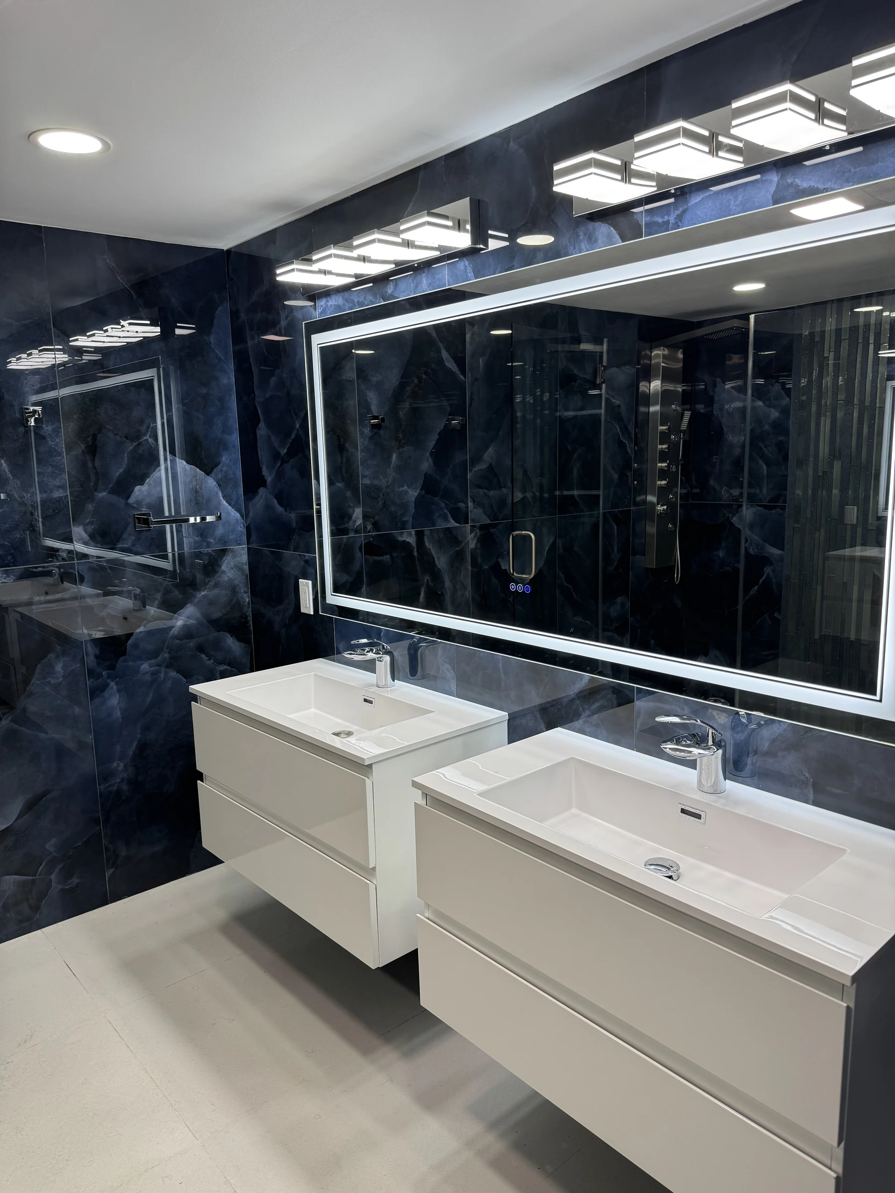 Bathroom with navy stone walls and a floating double vanity in Sherman Oaks