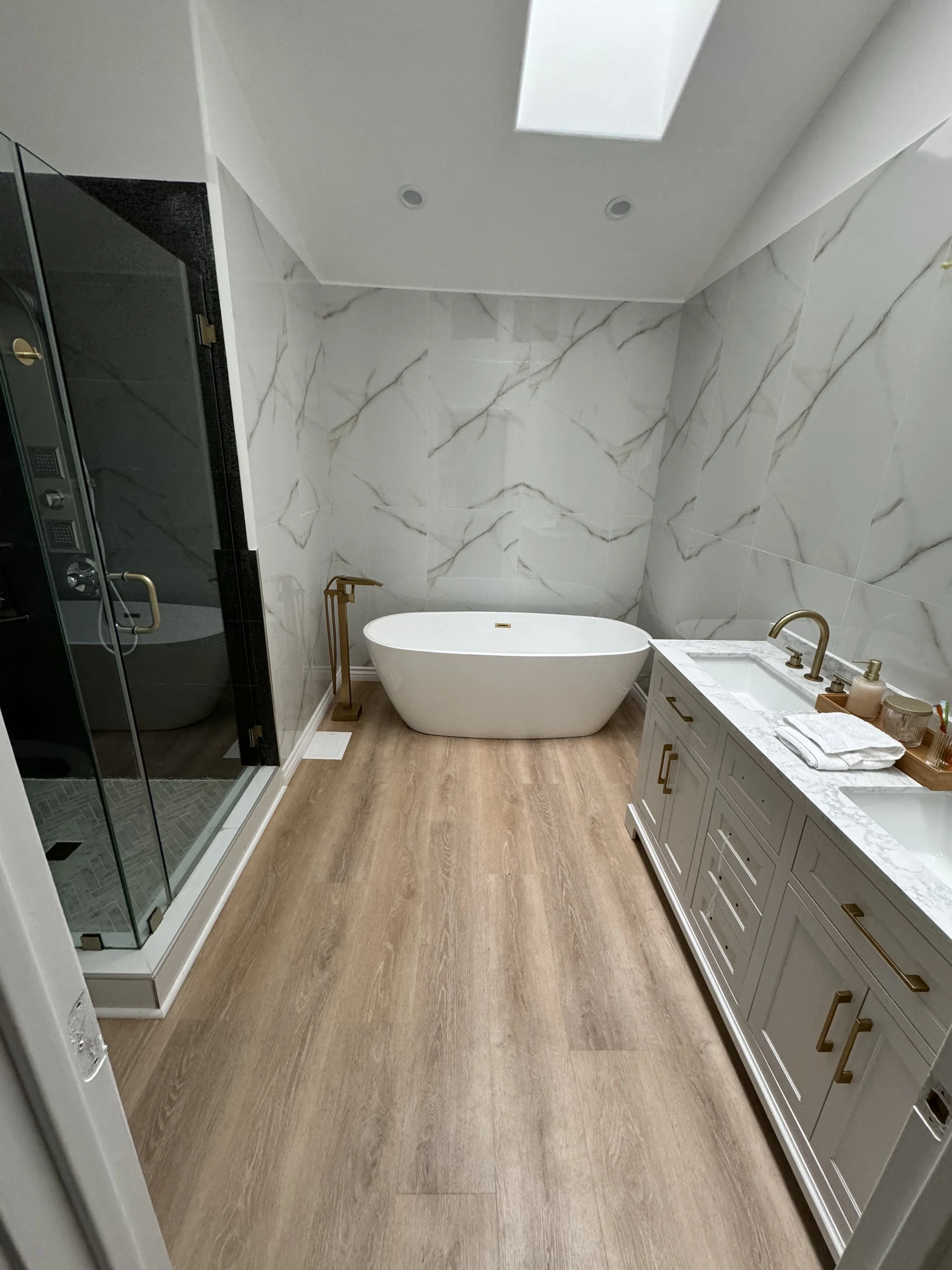 Same bathroom in Pacific Palisades after: marble-look walls, freestanding tub, double vanity