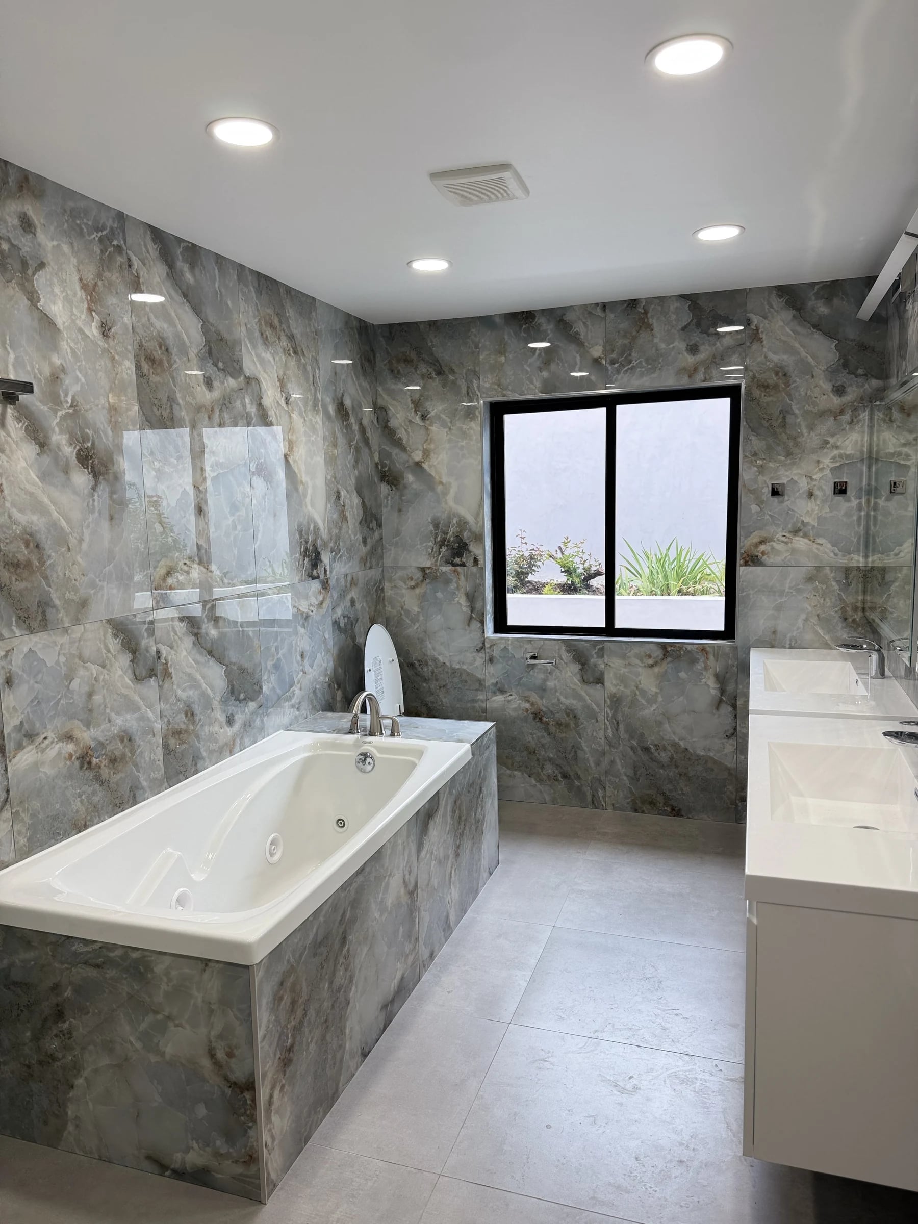 Bathroom with stone-look walls, a tiled soaking tub and a floating vanity in Mission Viejo