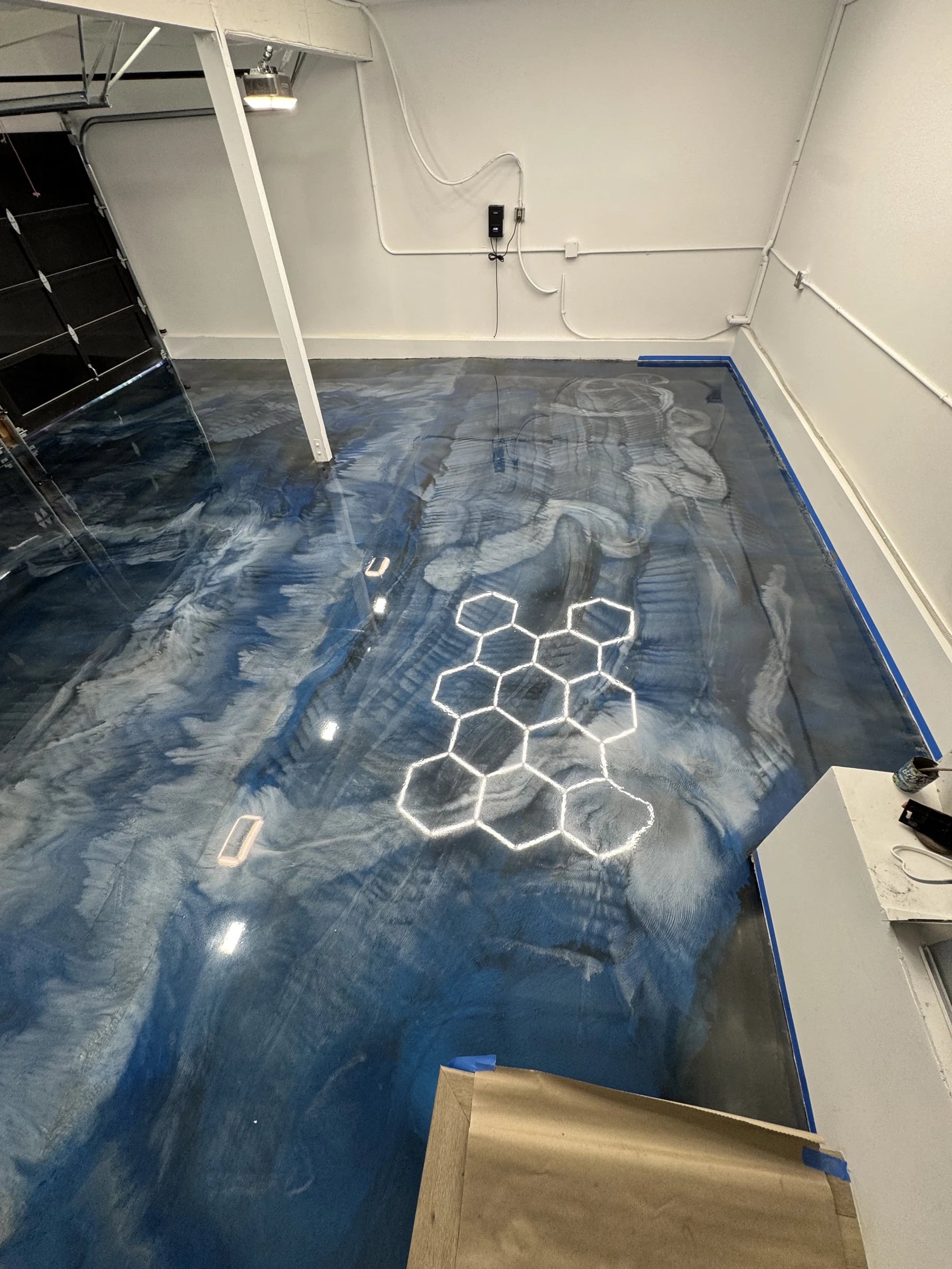 Garage with a blue metallic epoxy floor under hexagon lights in Orange