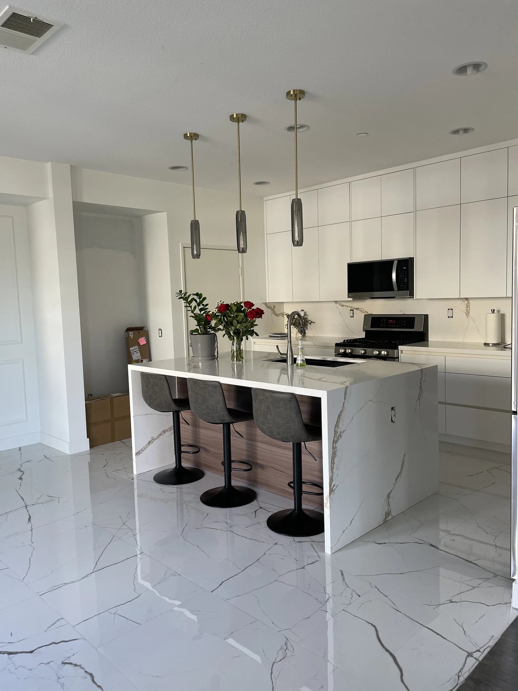Kitchen with a white waterfall island and marble-look floor