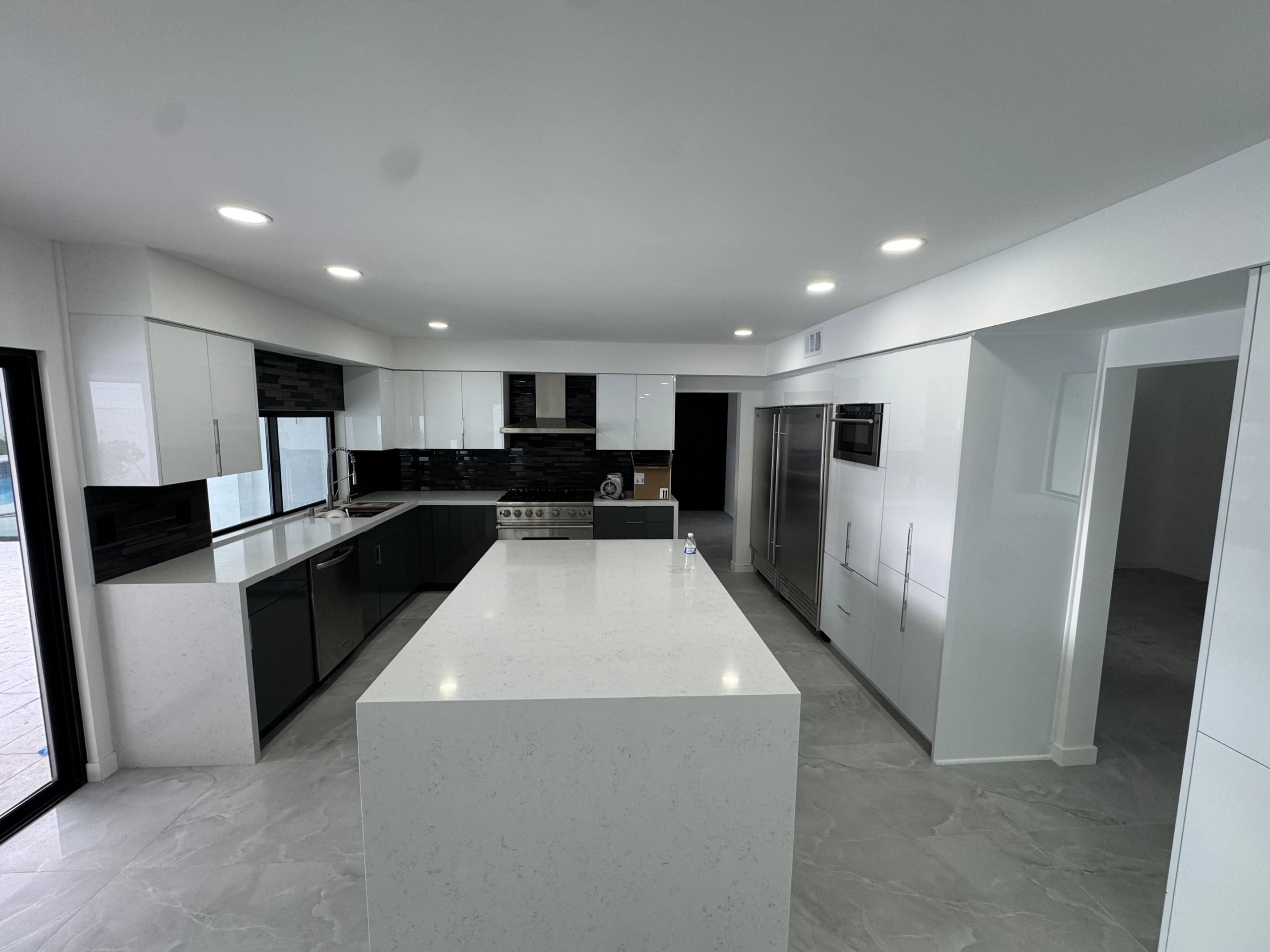 Open-plan kitchen with white cabinets and a long quartz island in Encino