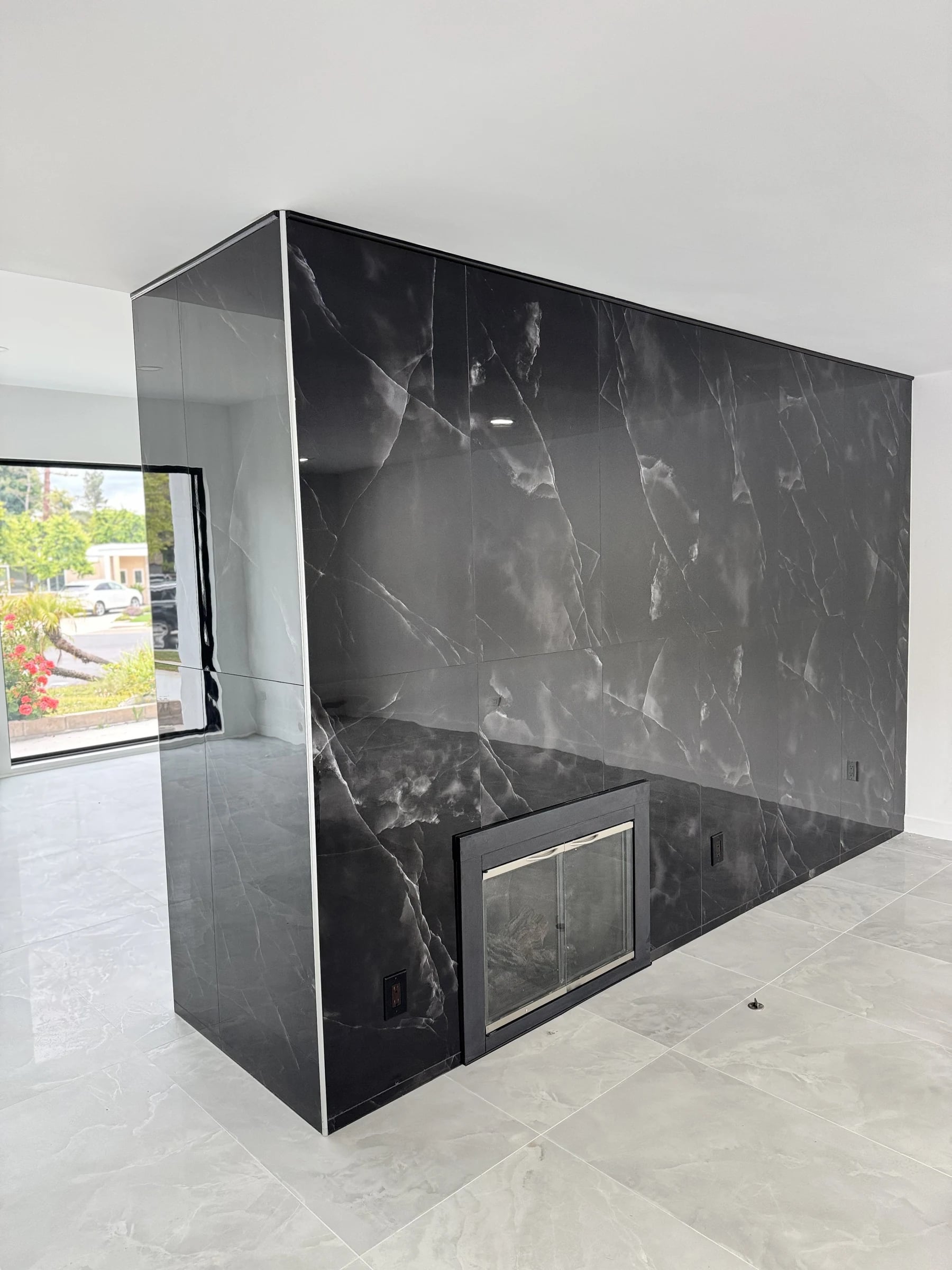 Black marble-look fireplace wall with a gold-trimmed firebox in Pacific Palisades