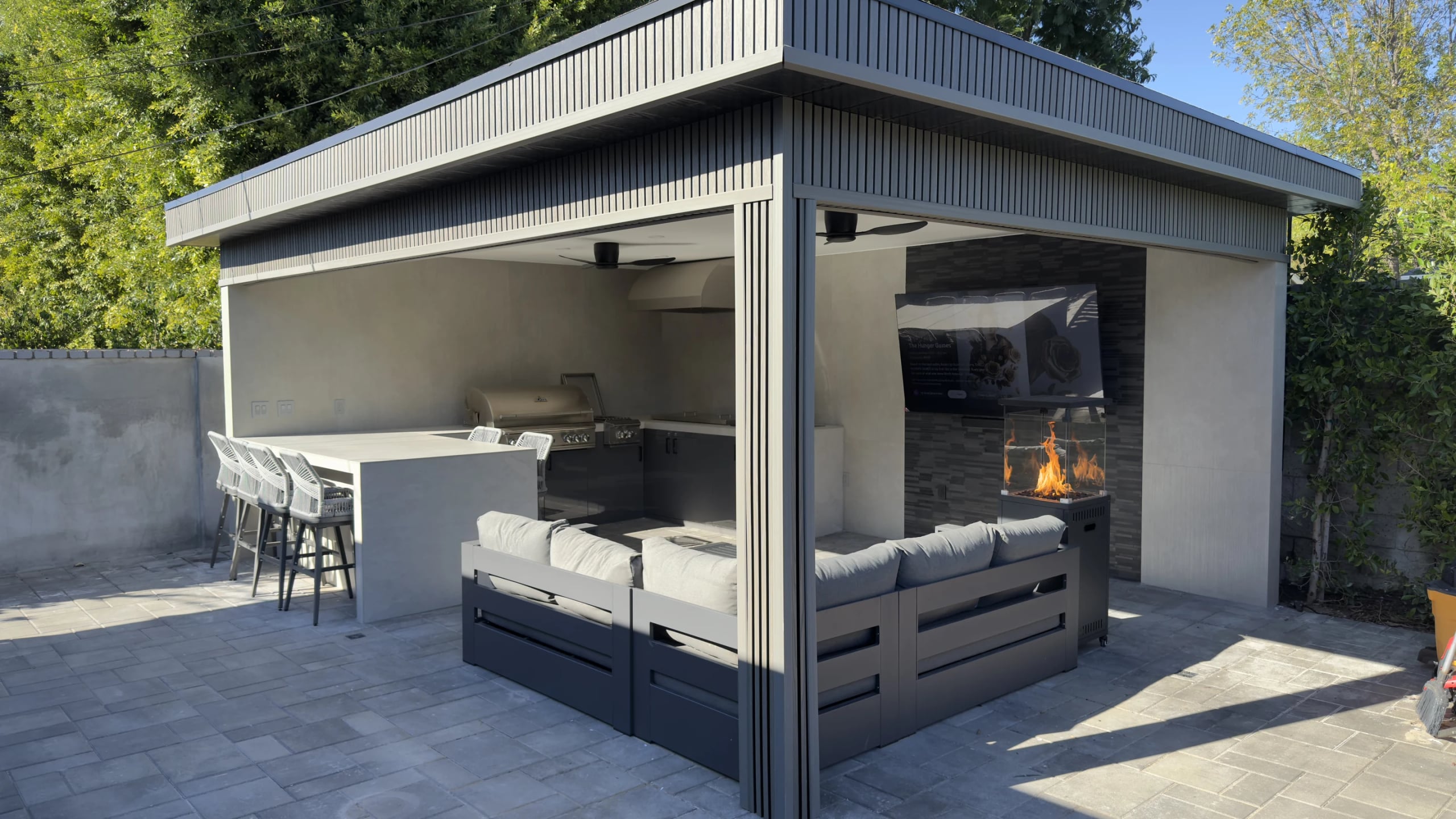 Covered outdoor pavilion with lounge seating and a fire table in Laguna Beach