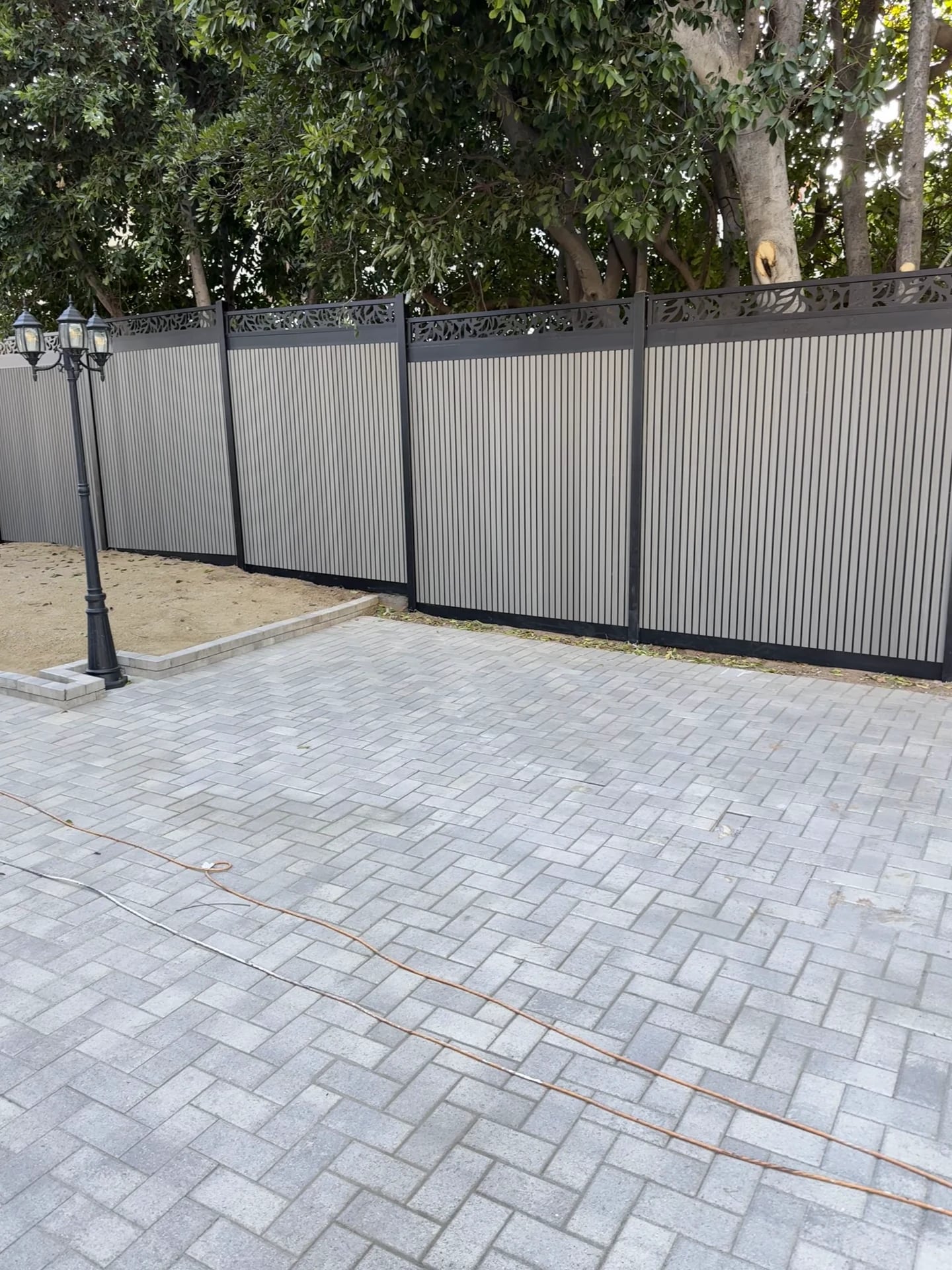 Paver patio along a new metal-panel privacy fence
